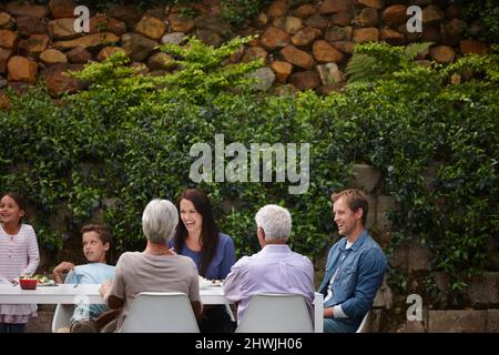 Passer du temps en famille de qualité à l'osme. Photo d'une famille de plusieurs générations heureuse ayant un repas ensemble à l'extérieur. Banque D'Images