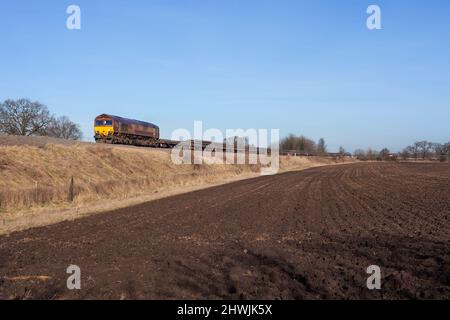 DB train de cargaison classe 66 diesel locomotive 66079 passant Morton, Gainsborough sur la ligne de Brigg, Lincolnshire avec un train de ballast pour réseau ferroviaire Banque D'Images