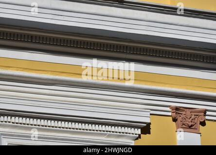 Ancienne façade de maison néoclassique avec un mur en stuc ocre, des colonnes d'ordre ionique et une garniture en plâtre blanc à Nafplio, Grèce. Banque D'Images