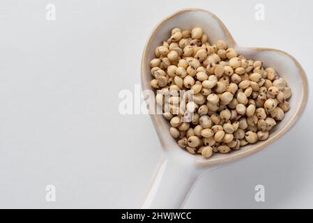 Graines de sorgho sur un cuillère en forme de coeur Banque D'Images