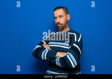 Profil vue latérale portrait de beau virile brunet Guy bras pliés espace de copie isolé sur fond bleu couleur. Banque D'Images