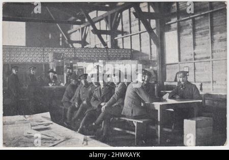 Refuge de repos et de loisirs de l'armée à Abbeville, France, 1916. La photo montre des soldats britanniques assis autour d'une table avec un comptoir de rafraîchissements à l'arrière-plan, occupés par une femme dans un chapeau. Un tableau avec une sélection de journaux est au premier plan Banque D'Images