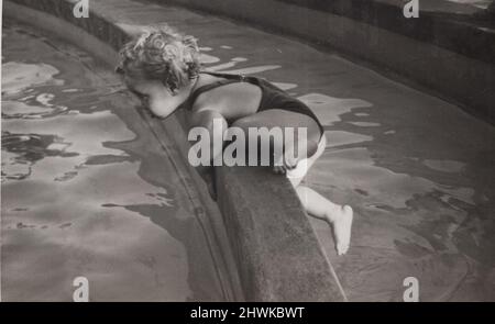 photo vintage noir et blanc sur un petit garçon monte jusqu'au bord d'une fontaine. Il est presque sauter dans l'eau. Perlude dangereuse de lui et irresponsabilité des parents. Période 1920s source: Photographie originale. INFO-AUTORISATION-DROITS-SUPPLÉMENTAIRES-NON-DISPONIBLE Banque D'Images