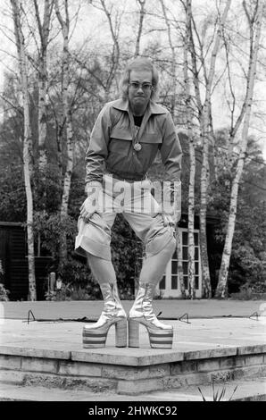 Elton John, chanteur, photographié chez lui à Virginia Water, en 1973. Il joue pour l'appareil photo, plus de 3 photos, tire des visages et montre ses jambes poilues et les dernières bottes de plate-forme, qui sont une taille de plate-forme de 5, et 8 pouces de haut. Ils sont argentés et rouges, avec ses initiales, et ont été faits pour mesurer en environ trois jours par Ken Todd de Kensington Market. Photo prise le 20th mars 1973 Banque D'Images