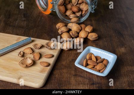 Bocal avec amandes à côté de quelques nuggets d'amandes fraîchement fendus. Banque D'Images