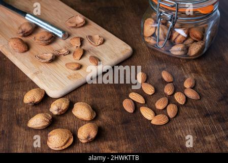 Bocal avec amandes à côté de quelques nuggets d'amandes fraîchement fendus. Banque D'Images