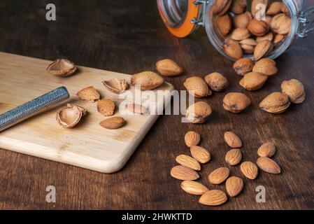 Bocal avec amandes à côté de quelques nuggets d'amandes fraîchement fendus. Banque D'Images