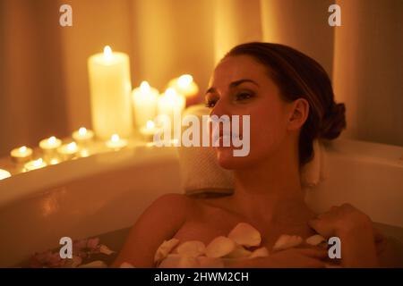 Apaisé par l'ambiance et un bain chaud. Photo courte d'une femme magnifique se détendant dans un bain aux chandelles. Banque D'Images