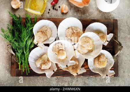 Coquilles Saint-Jacques crues sur plateau en bois de fruits de mer méditerranéens. Mollusques frais. Aequipecten opercularis. Jacobaeus Pecten Banque D'Images