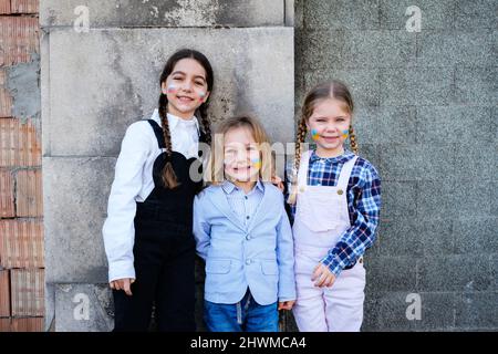 Portrait de trois enfants du caucase qui embrassent les visages avec des drapeaux russes et ukrainiens. Concept de paix, arrêter la guerre et l'amitié Banque D'Images