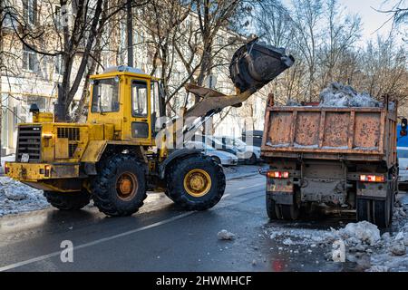 Moscou, Russie - le 02 mars 2022 : un tracteur d'un godet charge de la neige dans la voiture Banque D'Images