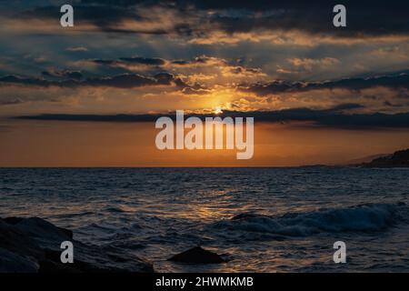 Vue sur la mer avec un ciel pittoresque et nuageux. Coucher de soleil sur une plage incroyable. Horizon lumineux doré. Vagues venant à la côte et en renier. Banque D'Images