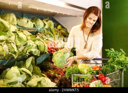 Prenez une autre laitue. Une jeune femme achetant des légumes à l'épicerie. Banque D'Images