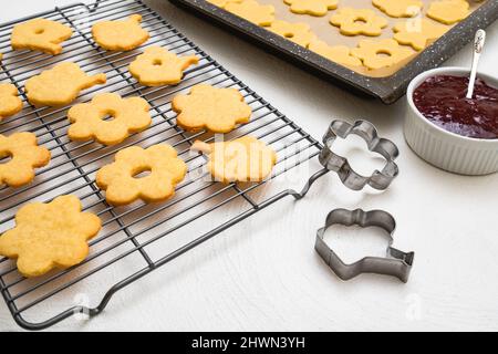 Biscuits sablés recette étape par étape. Délicieux dessert fait maison sur une plaque de cuisson et une grille de refroidissement sur une table de cuisine blanche Banque D'Images