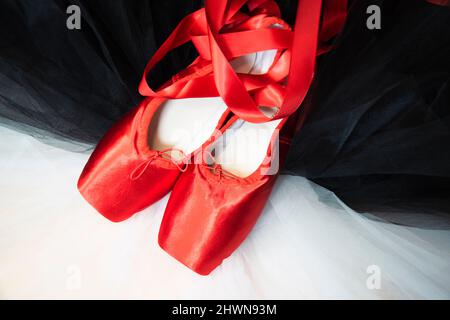 Ballet rouge chaussures de pointe reposant sur un tutu blanc et noir. Banque D'Images