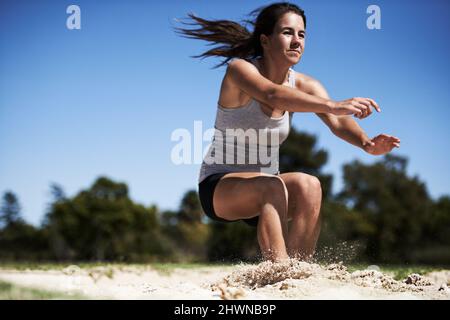 Aller aussi loin qu'elle peut. Une jeune femme fait un long saut. Banque D'Images