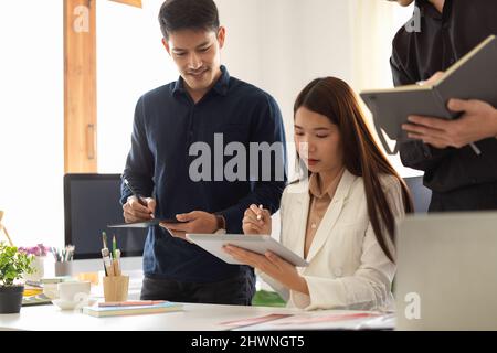 Une femme intelligente qui forme et coache deux hommes au bureau. Un groupe de gens d'affaires travaillent ensemble et prennent des notes sur leur note Banque D'Images