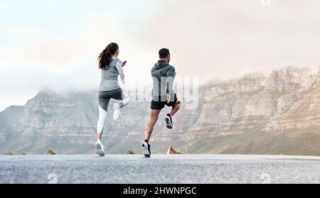 L'étirement permet d'améliorer la liberté de mouvement et de détendre les muscles. Vue arrière d'un jeune homme et d'une femme sportifs qui s'exercent ensemble à l'extérieur. Banque D'Images