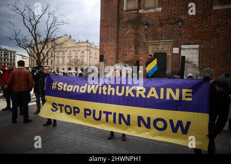 Cracovie, Pologne. 27th févr. 2022. Les manifestants tiennent une grande bannière disant « Stop Putin Now » pendant le rassemblement.depuis le début de l'agression russe en février, les gens du monde entier s'unissent pour montrer leur soutien à l'Ukraine. A Cracovie, entre autres manifestations, a eu lieu une chaîne de solidarité appelée 'Stand with Ukraine' (Credit image: © Vito Corleone/SOPA Images via ZUMA Press Wire) Banque D'Images