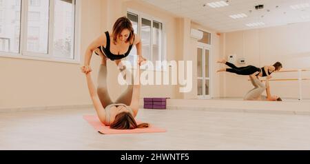 Deux femmes sportives pratiquant le yoga avec une posture avancée. Les jeunes femmes en vêtements de sport pratique l'équilibre corporel et l'harmonie ensemble. Yoga de fitness féminin Banque D'Images