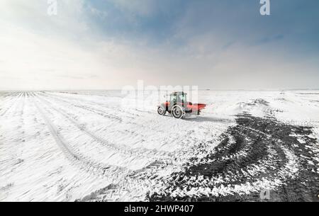 Agriculteur avec tracteur - semis semer les cultures aux champs agricoles en hiver et neige Banque D'Images