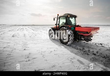 Agriculteur avec tracteur - semis semer les cultures aux champs agricoles en hiver et neige Banque D'Images