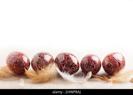 Traditionnel ukrainien Pysanka placé en ligne avec des plumes sur fond blanc. Oeufs de Pâques décorés, traditionnels pour la culture de l'Europe de l'est. Copier sp Banque D'Images