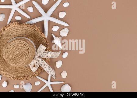 Étoile de mer blanche, coquillages et chapeau de paille d'été sur fond sable brun avec espace de copie Banque D'Images