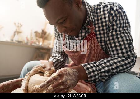 Jeune céramiste gai travaillant sur la roue de poterie Banque D'Images