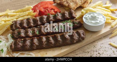 Shish kebab, doner souvlaki, viande rôtie cuisine traditionnelle de rue. Plat ethnique, pain pita, pomme de terre au yaourt et oignon tzatziki sur table en bois, gros plan Banque D'Images