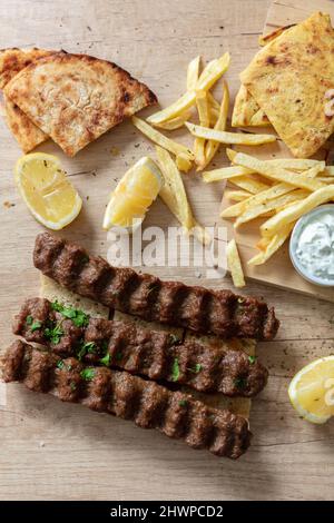 Kebab, donner souvlaki, viande rôtie cuisine traditionnelle de rue. Plat ethnique, pain pita, pomme de terre au yaourt et citron tzatziki sur une table en bois, vue sur le dessus Banque D'Images