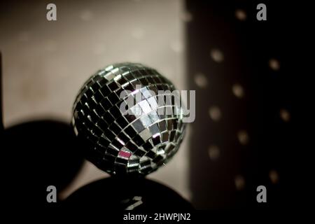 Le bal disco réfléchit la lumière dans la pièce. Une boule de petits miroirs se tient sur la surface du haut-parleur. Détails intérieurs en plein soleil. Banque D'Images