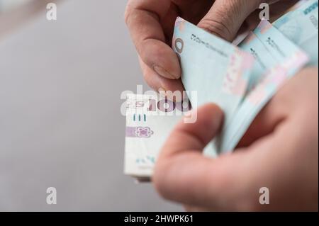 Gros plan des mains d'hommes comptant de l'argent. Un homme adulte compte les billets ukrainiens. Espèces en coupures de 1 000 hryvnias. Mise au point sélective. Banque D'Images