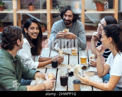 Hommes d'affaires souriants et femmes d'affaires ayant des burritos à la cafétéria de bureau Banque D'Images