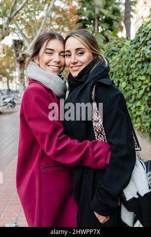 Des jeunes amis souriants s'embrassent Banque D'Images