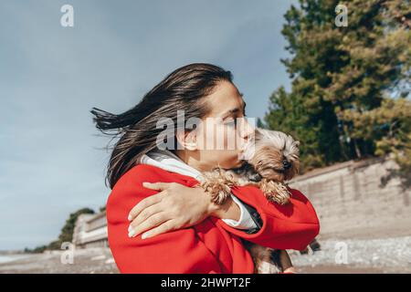 Femme embrassant Yorkshire terrier à la plage Banque D'Images