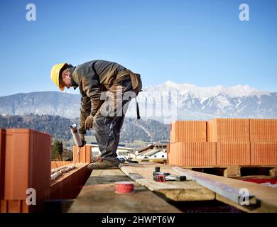 Briques de fixation de briques avec colle tenant pistolet à mastic sur le chantier de construction Banque D'Images