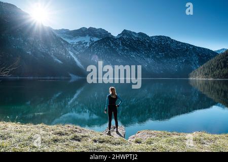 Femme à la main sur la hanche regardant à travers le lac Plansee aux Alpes d'Ammergau, Reutte, Tyrol, Autriche Banque D'Images