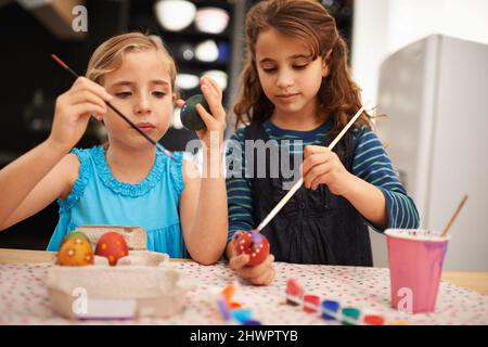 Théyre dans leurs arts et métiers. Photo de deux petites filles peignant des œufs de pâques. Banque D'Images