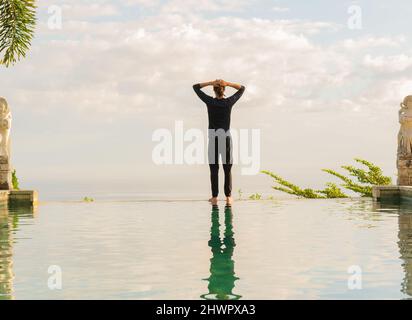 Un homme debout au bord de la piscine à débordement Banque D'Images