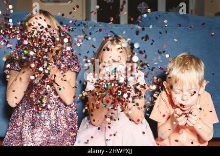 Confetti soufflants de frères et sœurs à la maison Banque D'Images