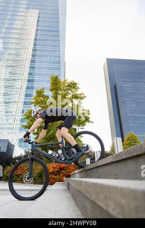 Un jeune cycliste fait des cascades avec un vélo sur les marches Banque D'Images