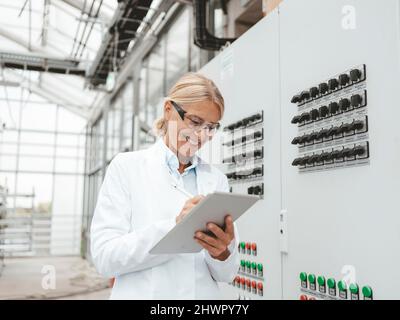 Scientifique souriant utilisant une tablette PC dans l'industrie Banque D'Images