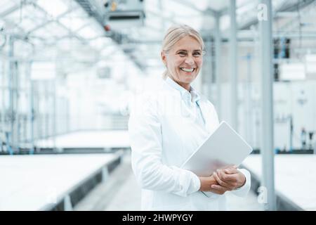 Un agronome souriant avec une tablette PC dans l'industrie Banque D'Images