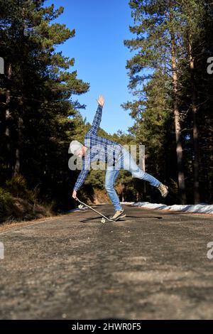 Homme avec la main levée pratiquant avec le skateboard Banque D'Images