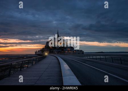 France, Normandie, ciel nuageux sur pont reliant l'île du Mont-Saint-Michel au crépuscule Banque D'Images