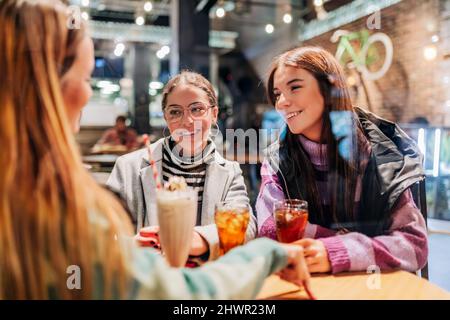 Amis souriants prenant un verre au café Banque D'Images