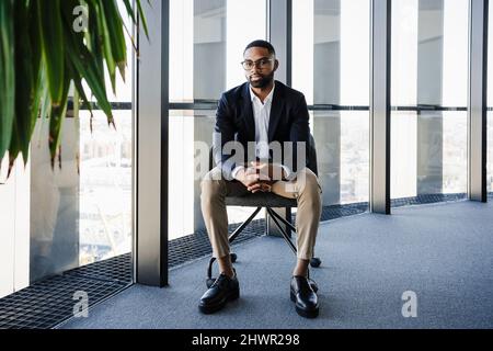 Homme d'affaires avec les mains classed assis sur la chaise dans le bureau Banque D'Images