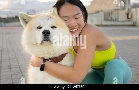 Jeune femme souriante embrassant un chien sur la piste de marche Banque D'Images