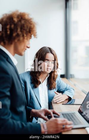 Femme travaillant discutant de stratégie avec un homme d'affaires utilisant un ordinateur portable au bureau Banque D'Images
